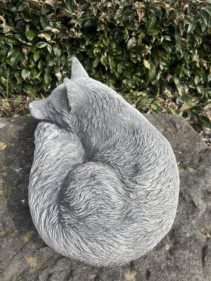 handcrafted grey concrete fox statue in a curled sleeping position for outdoor garden decor.