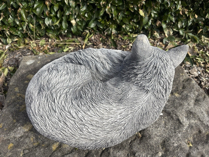 handcrafted grey concrete fox ornament in a curled sleeping position on a stone surface