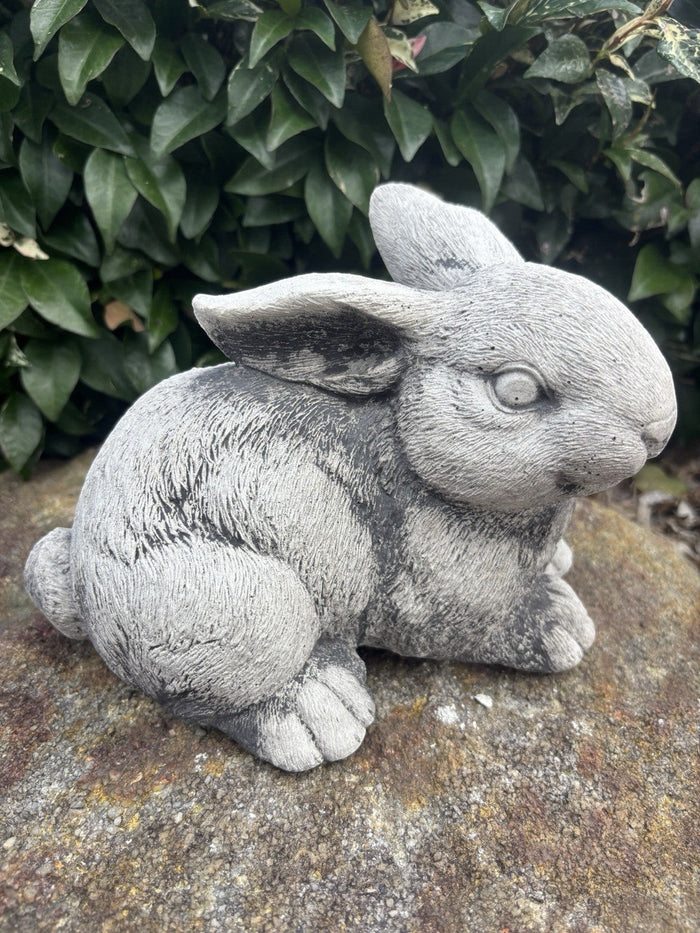 handcrafted grey concrete rabbit sculpture with realistic fur texture in a garden setting
