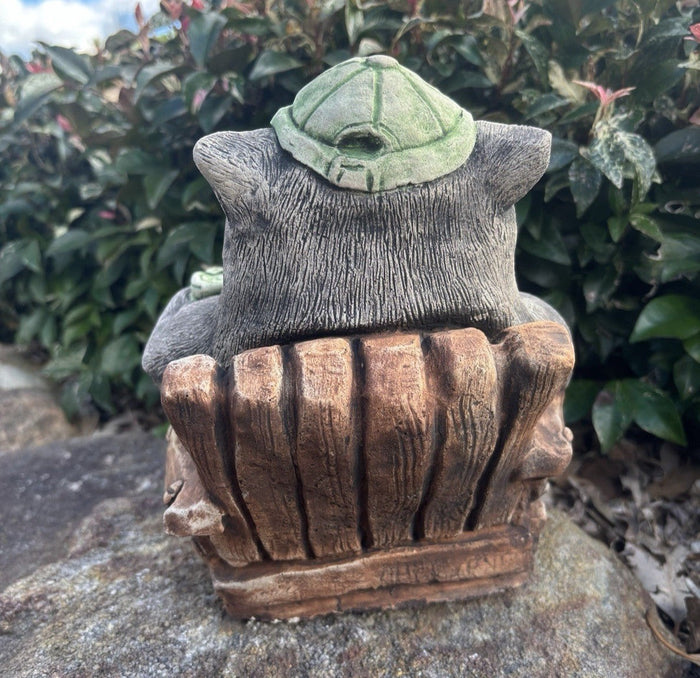 Back view of 22nice4me Garden Statues concrete wombat wearing a green cap and relaxing in a wooden-style chair