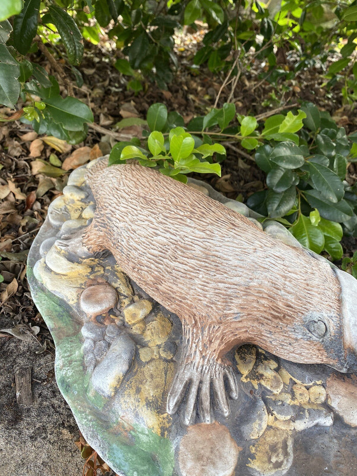 22nice4me Garden Statues hand-painted concrete platypus sculpture resting on a rocky base in a garden setting