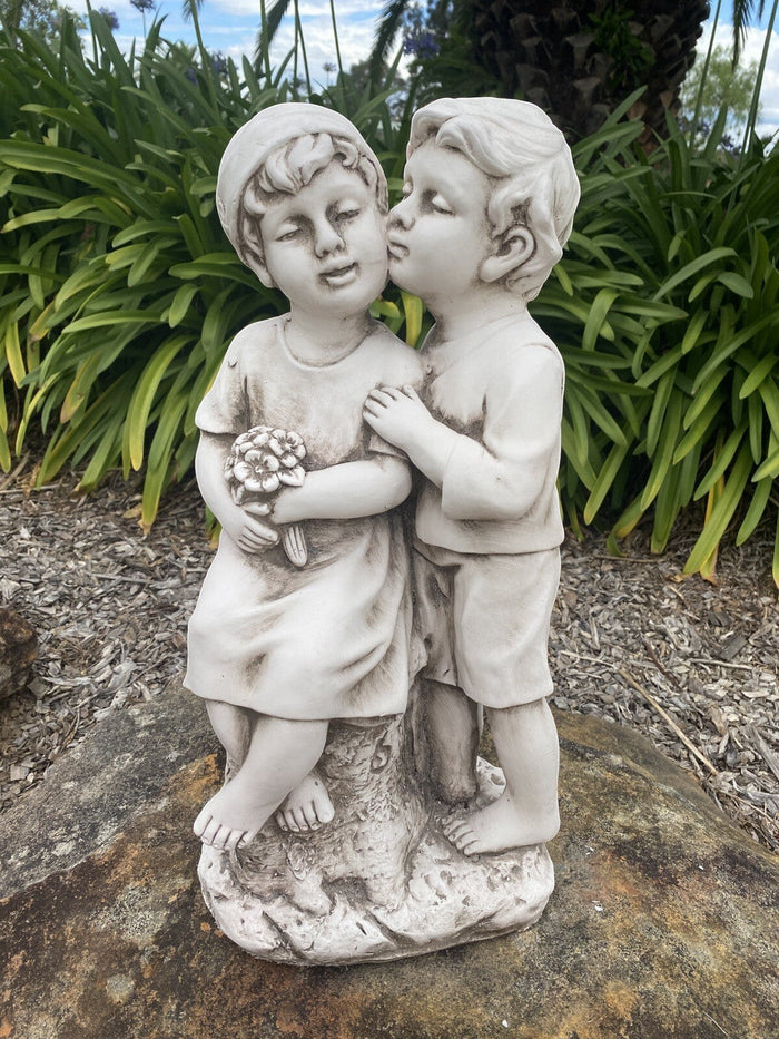 22nice4me Garden Statues antique white fibre clay sculpture of two children kissing, holding a bouquet of flowers.