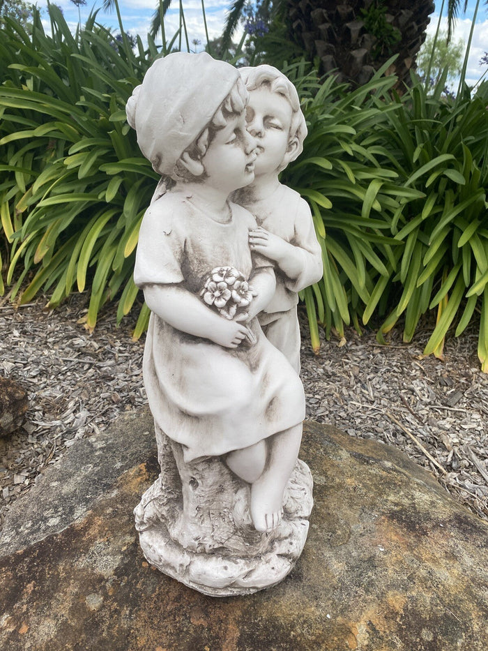 22nice4me Garden Statues antique white fibre clay sculpture of two children kissing, holding a bouquet of flowers.