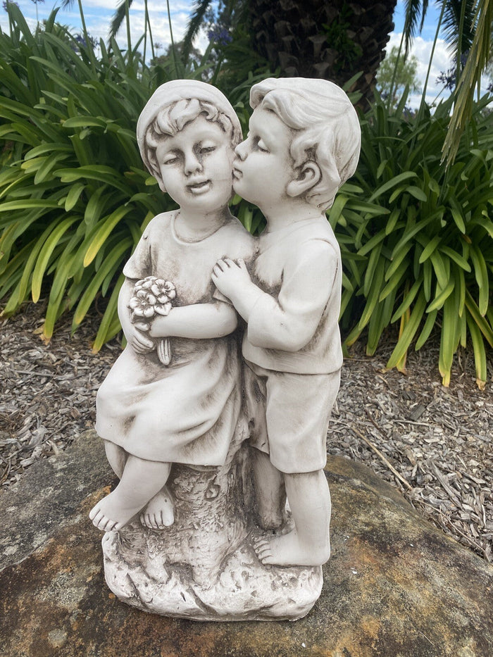 22nice4me Garden Statues antique white fibre clay sculpture of two children kissing, one holding a flower bouquet.