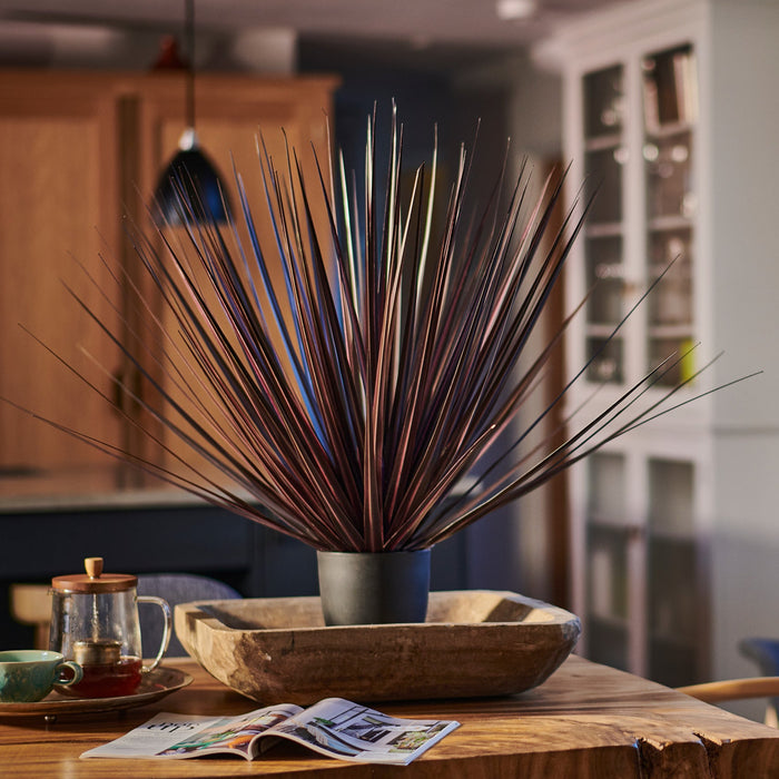 Decorative plant in a vase on a wooden table with a blurred background