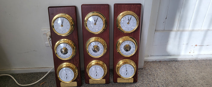 Three wooden weather stations with barometer, hygrometer, and clock dials in gold trim