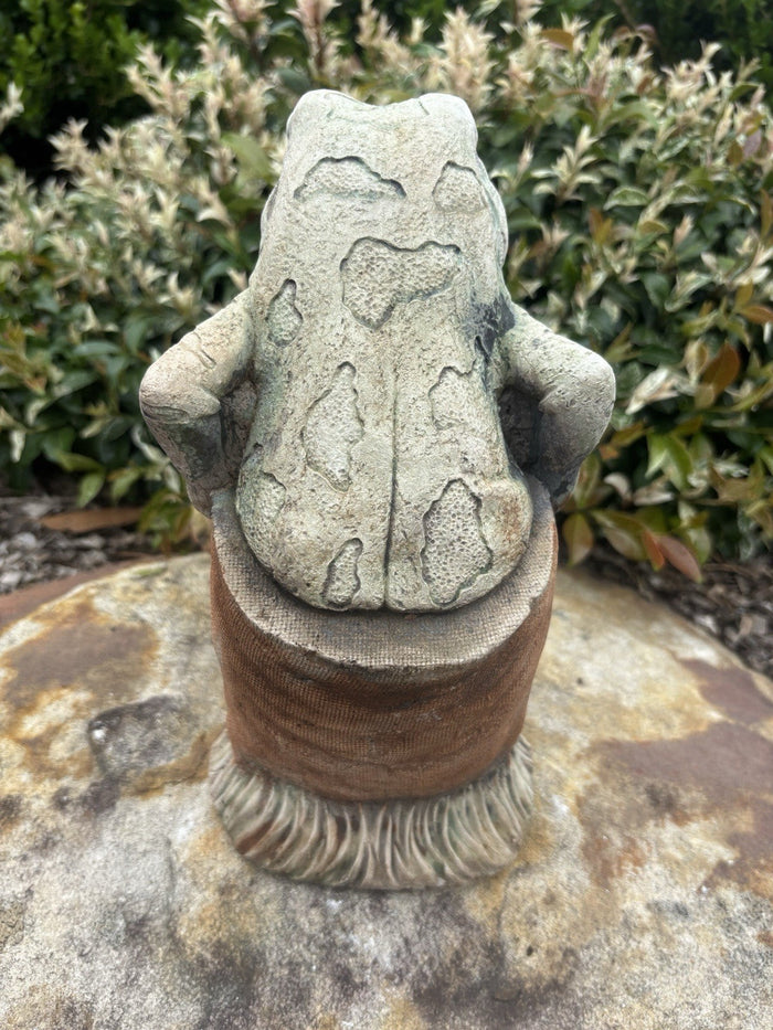 22nice4me Garden Statues hand-painted concrete frog sitting in a potato sack, back view in a garden setting.