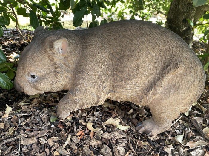 22nice4me Garden Statues hand-painted resin wombat figurine standing in a garden setting with mulch and leaves