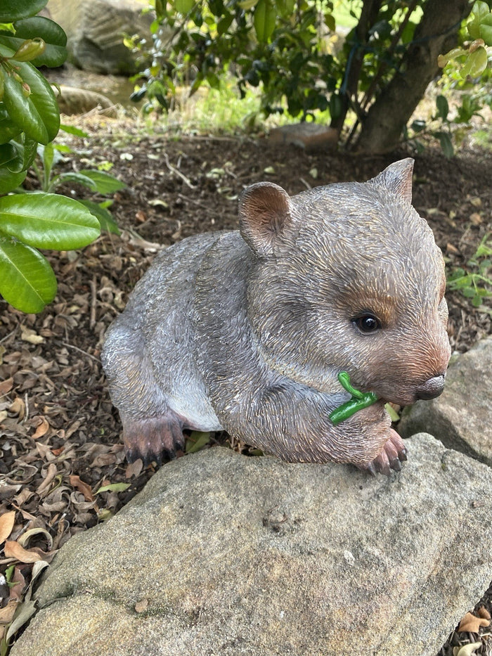 22nice4me Garden Statues hand painted resin wombat ornament eating a green leaf in a natural outdoor garden setting