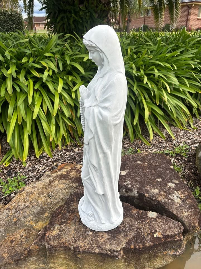 22nice4me Garden Statues resin Virgin Mary statue in a prayer pose, placed on a rock in an outdoor garden setting.