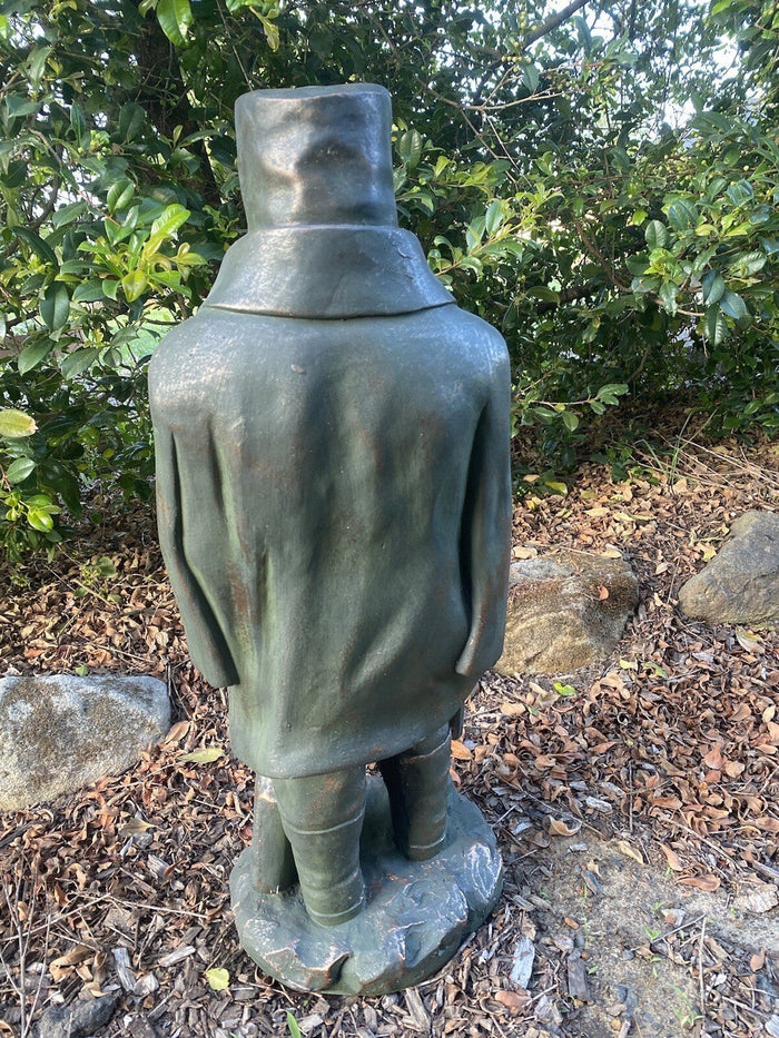 Back view of a 22nice4me Garden Statues Ned Kelly fiber clay figurine with a rustic hand-painted finish in a garden.