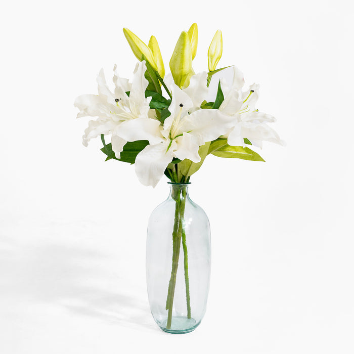 Clear glass vase with white lilies on a white background