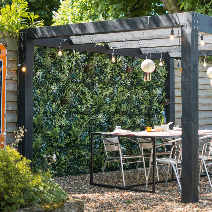 Outdoor patio area with a pergola, table, and chairs in a garden setting.